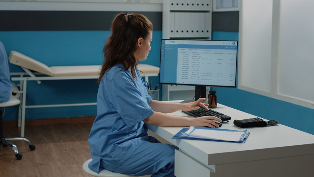 A doctor on a computer looks for a file.