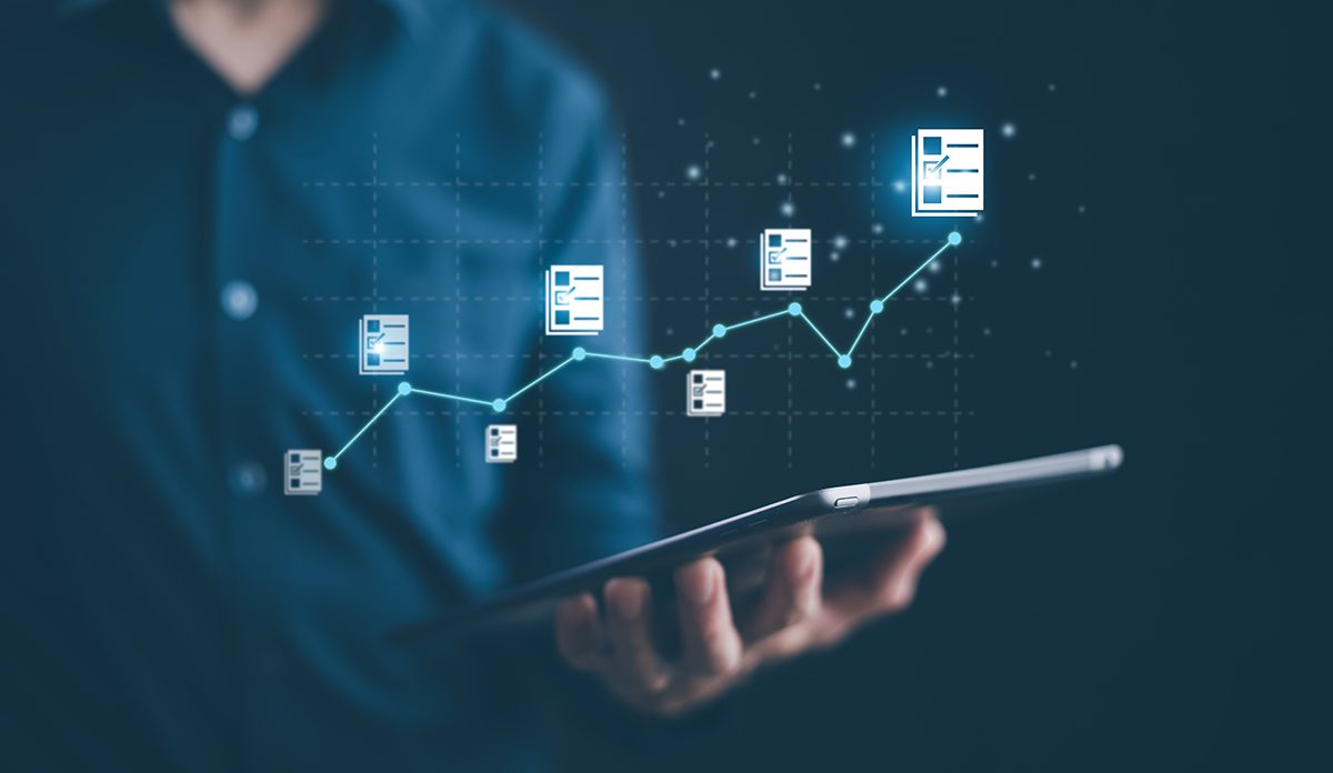 A person in a dress shirt holds a tablet with a graphic overlay of checklists moving along an increasing graph line.