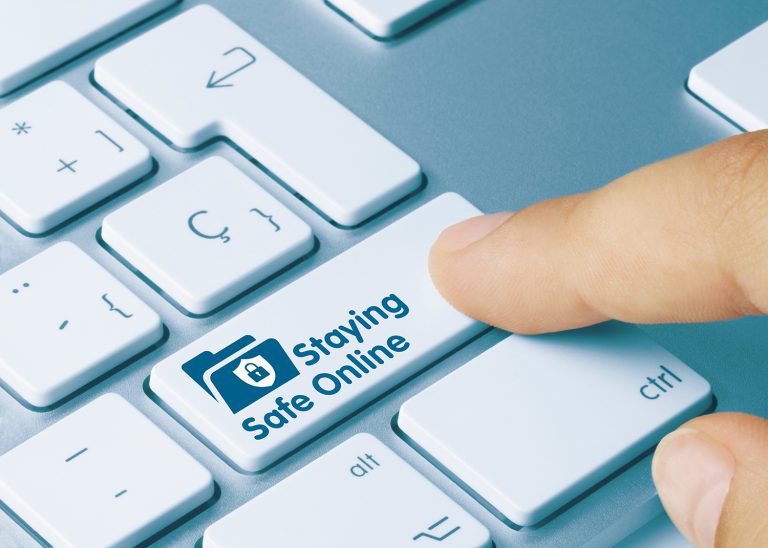 A pointer finger pressing a "Staying Safe Online" key on a keyboard.